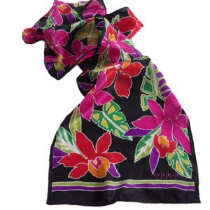 May include: A black silk scarf with a vibrant floral pattern. The design features large, stylized flowers in shades of pink, red, and orange, with green leaves against a black background. The scarf has a purple and black border.