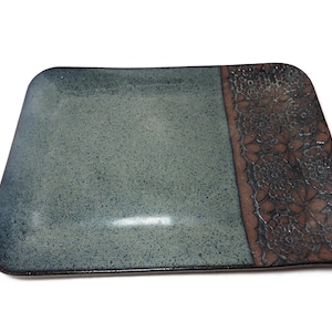May include: A rectangular ceramic serving tray with a blue-green glaze and a brown border with a floral design.