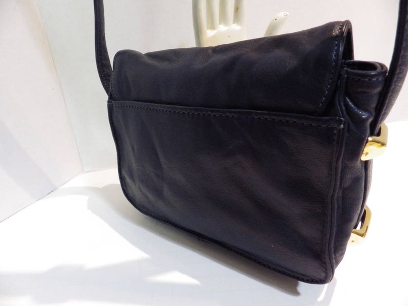 May include: A black leather shoulder bag with gold hardware. The bag has a flap closure and a single strap.