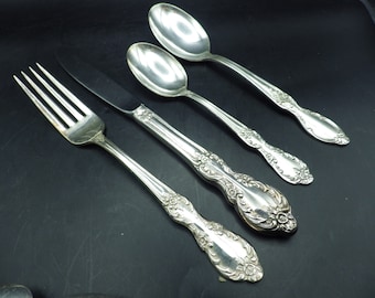 May include: A set of four silver-plated flatware pieces, including a fork, knife, and two spoons. The pieces have ornate floral designs.