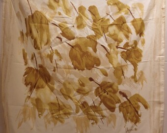 Peut inclure: Un foulard en soie blanc avec un motif abstrait de feuilles brunes. Le foulard porte une signature en bas à droite qui dit "Usagi"