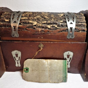 May include: A wooden box with a log lid and metal accents. The box has a small tag attached to it with handwritten text.