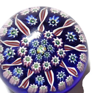 Pode incluir: Um pisa-papéis de vidro azul com um padrão floral branco, rosa e vermelho.