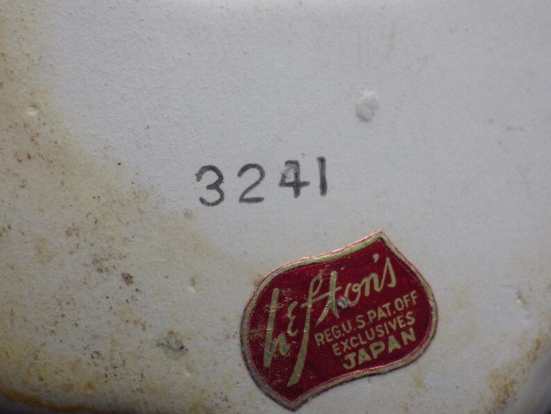 May include: Close-up of a white ceramic surface with the number "3241" printed in black. A red and gold "Lefton's" sticker is affixed to the surface, with text indicating it is a U.S. patent and exclusive product from Japan.