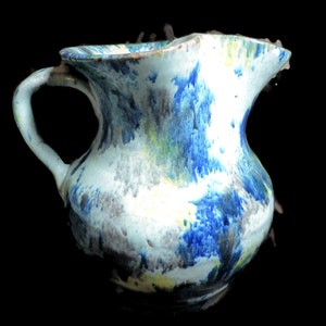 May include: A blue and white ceramic pitcher with a mottled glaze. The pitcher has a wide mouth and a handle.