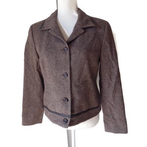 May include: A brown tweed blazer with a black trim around the edges and four black buttons down the front.