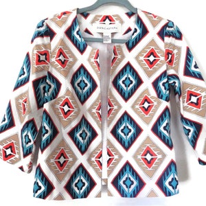 May include: A white open-front jacket with a geometric pattern in shades of blue, red, and brown. The label "Doncaster" is visible on the inside of the collar.