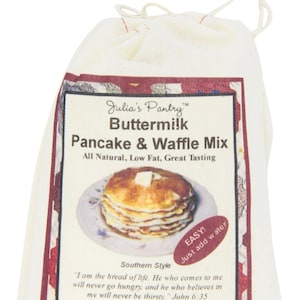 May include: A white canvas bag with a red and white label that says "Julia's Pantry™ Buttermilk Pancake & Waffle Mix All Natural, Low Fat, Great Tasting" and features a photo of a stack of pancakes. The label also says "EASY! Just add water" and "Southern Style". The label includes a quote from John 6:35 and the weight of the mix is 10oz (284g).