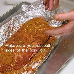 Puede incluir: Primer plano de un lomo de cerdo cubierto con una mezcla de especias y envuelto en papel de aluminio. El texto "Make sure you rub both sides of the pork loin" es visible en la imagen.