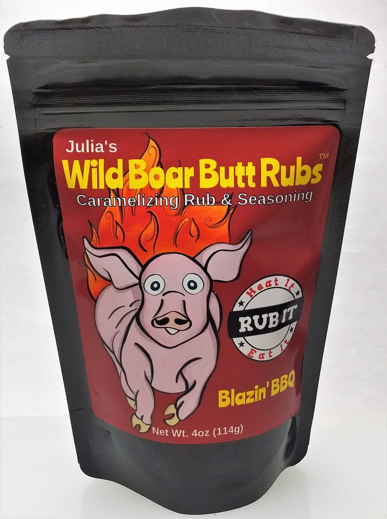 Puede incluir: Una bolsa negra resellable con una etiqueta roja que presenta un cerdo de dibujos animados corriendo con llamas. La etiqueta dice "Julia's Wild Boar Butt Rubs Caramelizing Rub & Seasoning" y "Heat It Rub It Eat It Blazin' BBQ". La bolsa contiene 114 gramos de condimento.