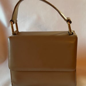 May include: A brown leather handbag with a top handle and gold hardware.