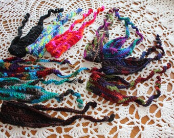 May include: A collection of colorful crocheted headbands with various patterns and colors, including black, brown, red, blue, green, and purple.