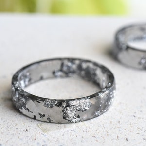 May include: Two silver rings with a textured, speckled finish. The rings are made of a clear material with silver flakes embedded in it.