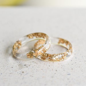 May include: Two clear resin rings with gold flakes embedded inside. The rings are stacked on top of each other.