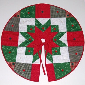 May include: A red, green, and white quilted Christmas tree skirt with a star design and red buttons. The skirt has a tie closure.