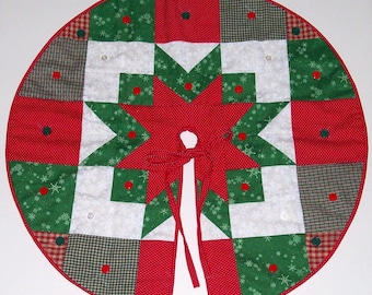 May include: A red, green, and white quilted Christmas tree skirt with a star design and red buttons. The skirt has a tie closure.