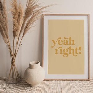 Puede incluir: Una impresión enmarcada con un fondo marrón claro y el texto "yeah right!" en color amarillo-naranja. La impresión está en un marco de madera y está sobre una superficie marrón claro.