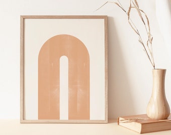 May include: A framed print of an abstract arch shape in a peach color on a white background. The frame is light wood.