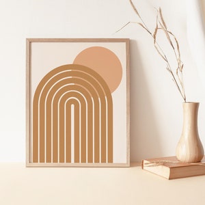 May include: A framed print with a minimalist design featuring a brown archway with a peach-coloured circle above it. The print has a white background and is framed in a light wood frame.