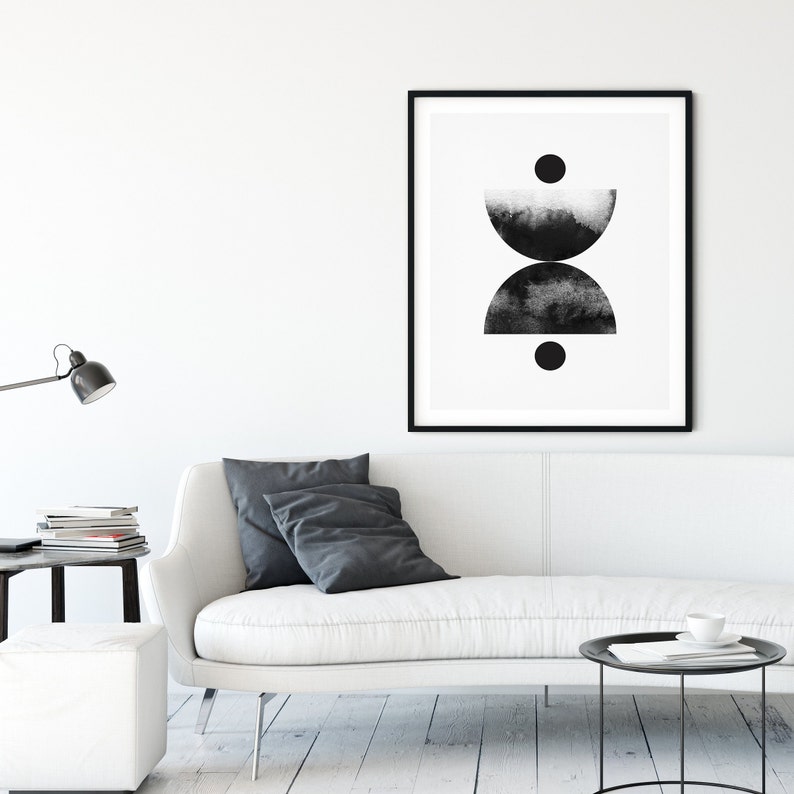 May include: Black and white abstract art print with two half circles and two circles. The print is framed in a black frame and hanging on a white wall.