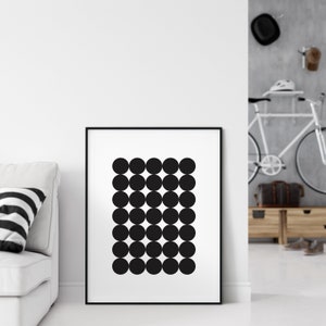 May include: Black and white abstract art print with a geometric pattern of circles in a grid. The print is framed in a black frame and is hanging on a white wall.