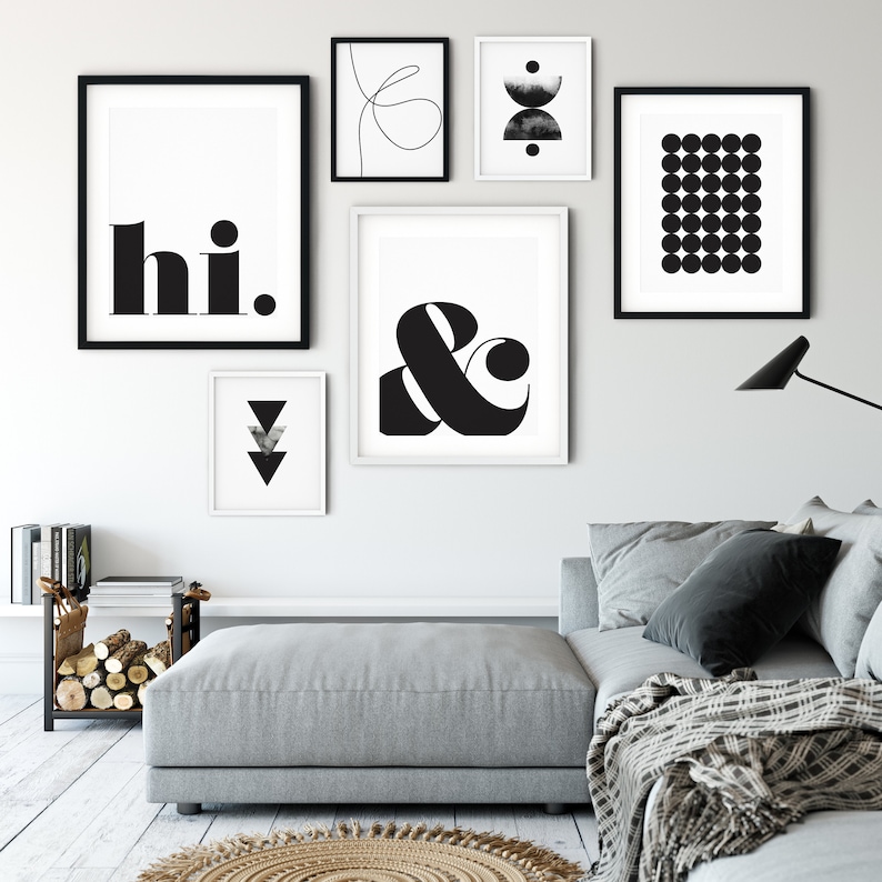 May include: A gallery wall with black and white framed prints. The prints feature geometric shapes, abstract designs, and the words "hi." and "&".