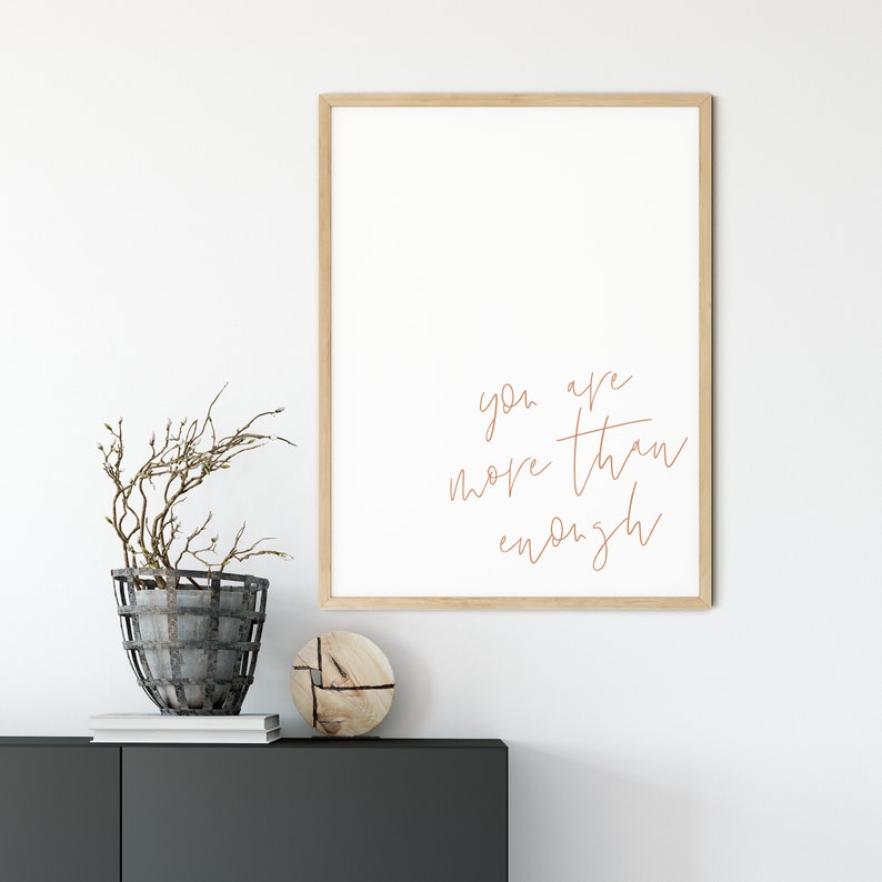 May include: A framed print with a white background and the text "you are more than enough" written in brown cursive script.