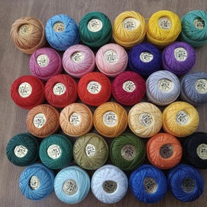 May include: Assortment of colorful embroidery floss spools in various shades of red, blue, green, yellow, orange, pink, and brown.