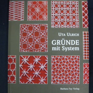 May include: Book cover with the title "GRÜNDE mit System" by Uta Ulrich. The cover features a variety of white lace patterns on a red background.