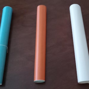 May include: Three rolls of vinyl adhesive paper. The rolls are teal, orange, and white.