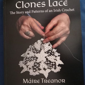 May include: A book titled "Clones Lace" with the subtitle "The Story and Patterns of an Irish Crochet." The cover features a close-up of hands working with white lace, with the author's name, Máire Treanor, and "Third Edition" text.