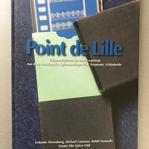 May include: A blue book titled "Point de Lille" with the subtitle "Tüllgrundspitzen aus dem Erzgebirge" and "Aus dem Nachlass des Spitzenverlegers G.F. Baumann, Schönheide". The book is about lace and features a photo of lace on the cover.