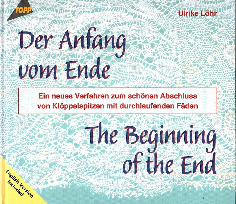 May include: A book cover with the title "Der Anfang vom Ende" in dark blue script over a light blue background with a lace pattern. The English translation "The Beginning of the End" is also displayed.
