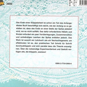 May include: A book cover with a white lace pattern and text in German. The book is titled "TOPP 2695" and includes the ISBN 3-7724-2695-6. The cover has a red border and a price tag.