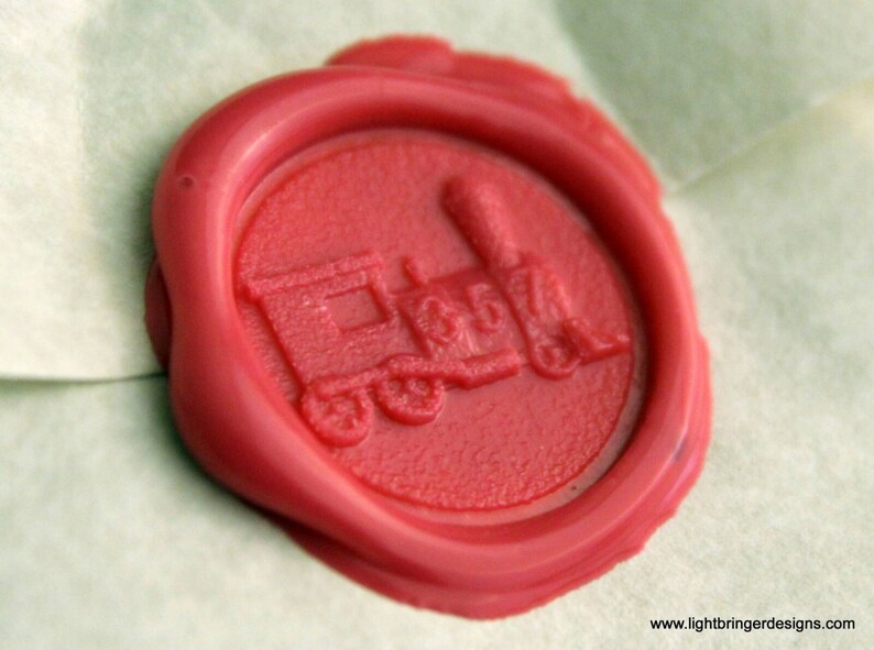 May include: A red wax seal with a detailed image of a train engine. The seal is on a white background.