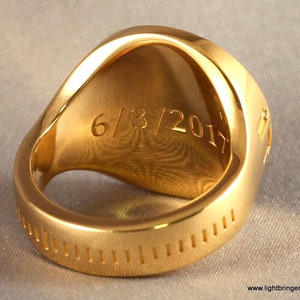 May include: A gold ring with a smooth, rounded top and a textured band. The inside of the ring is engraved with the date "6/8/2017".