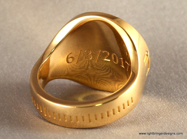 May include: A gold ring with a smooth, rounded top and a textured band. The inside of the ring is engraved with the date "6/8/2017".