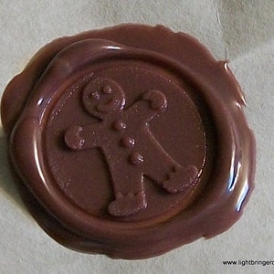 May include: A brown wax seal with a gingerbread man design.