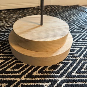 May include: Two round wooden bases stacked on top of each other. The top base is slightly smaller than the bottom base. Both bases are made of light wood with a natural finish.