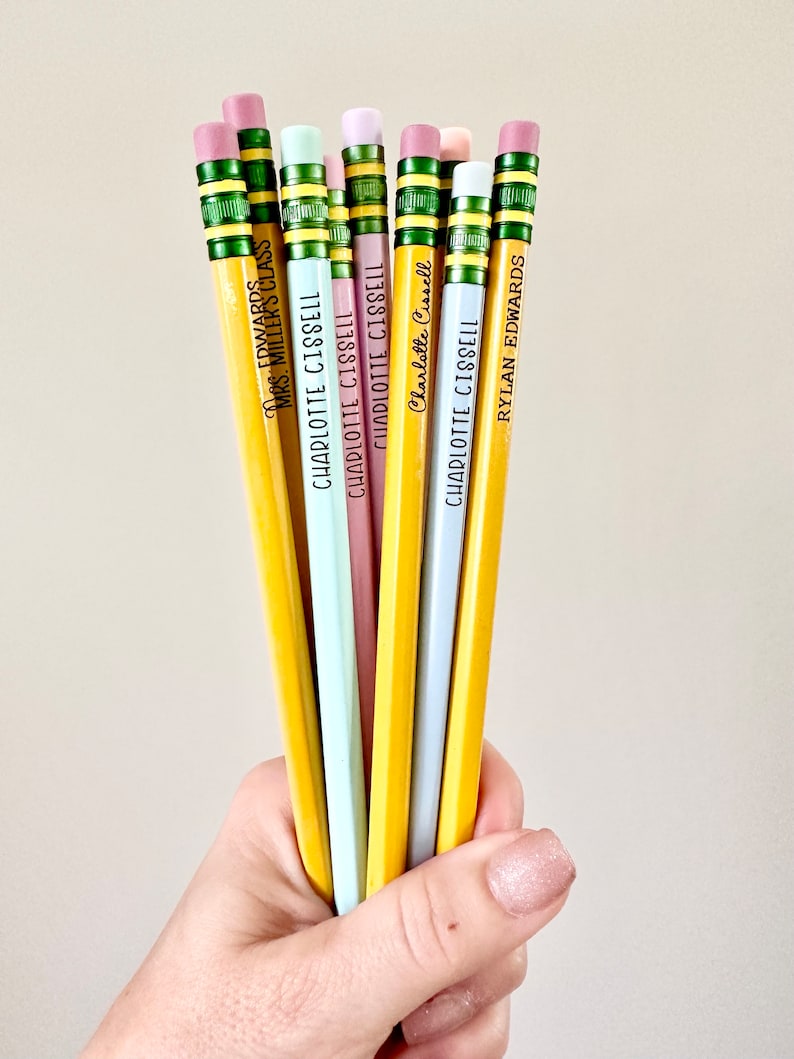 May include: A bunch of yellow pencils with different colored erasers and personalized names, including "Mrs. Millers Class", "Charlotte Cissell", and "Rylan Edwards".