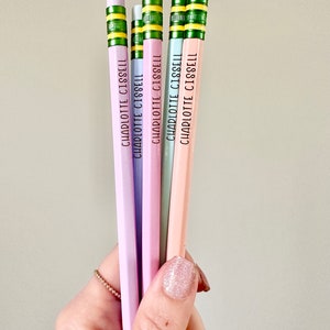 May include: Five pastel colored pencils with green and yellow stripes and the name "CHARLOTTE CISSELL" printed on each pencil.
