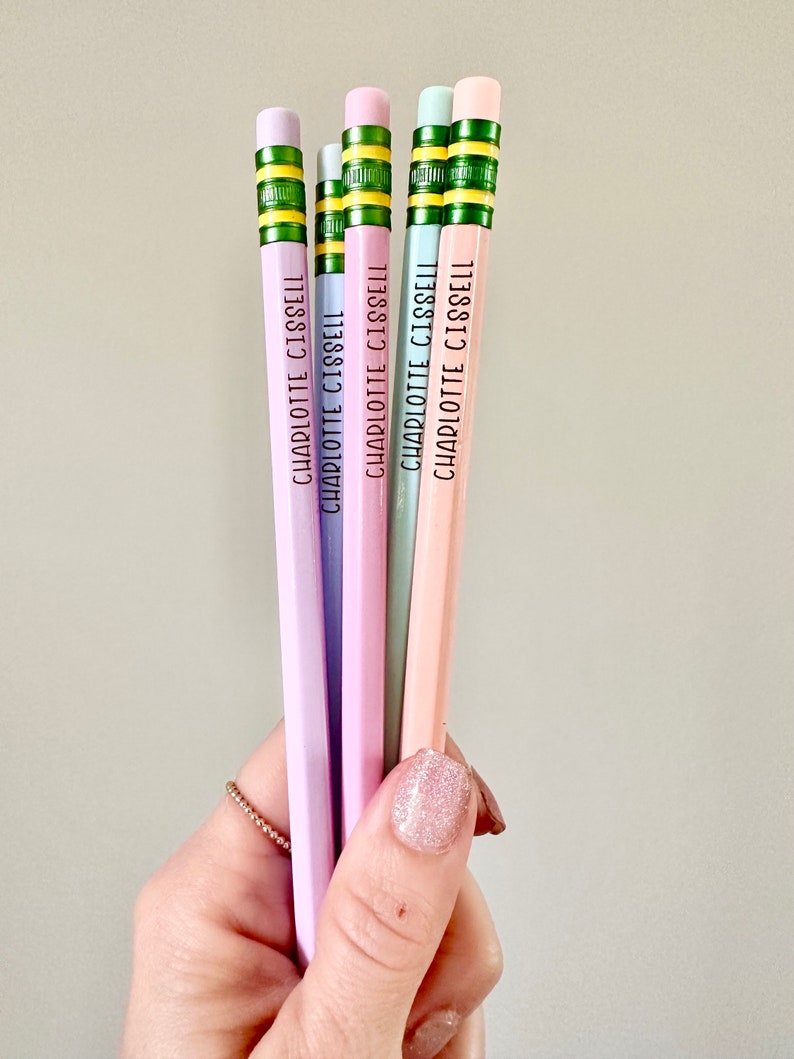 May include: Five pastel colored pencils with green and yellow stripes and the name "CHARLOTTE CISSELL" printed on each pencil.