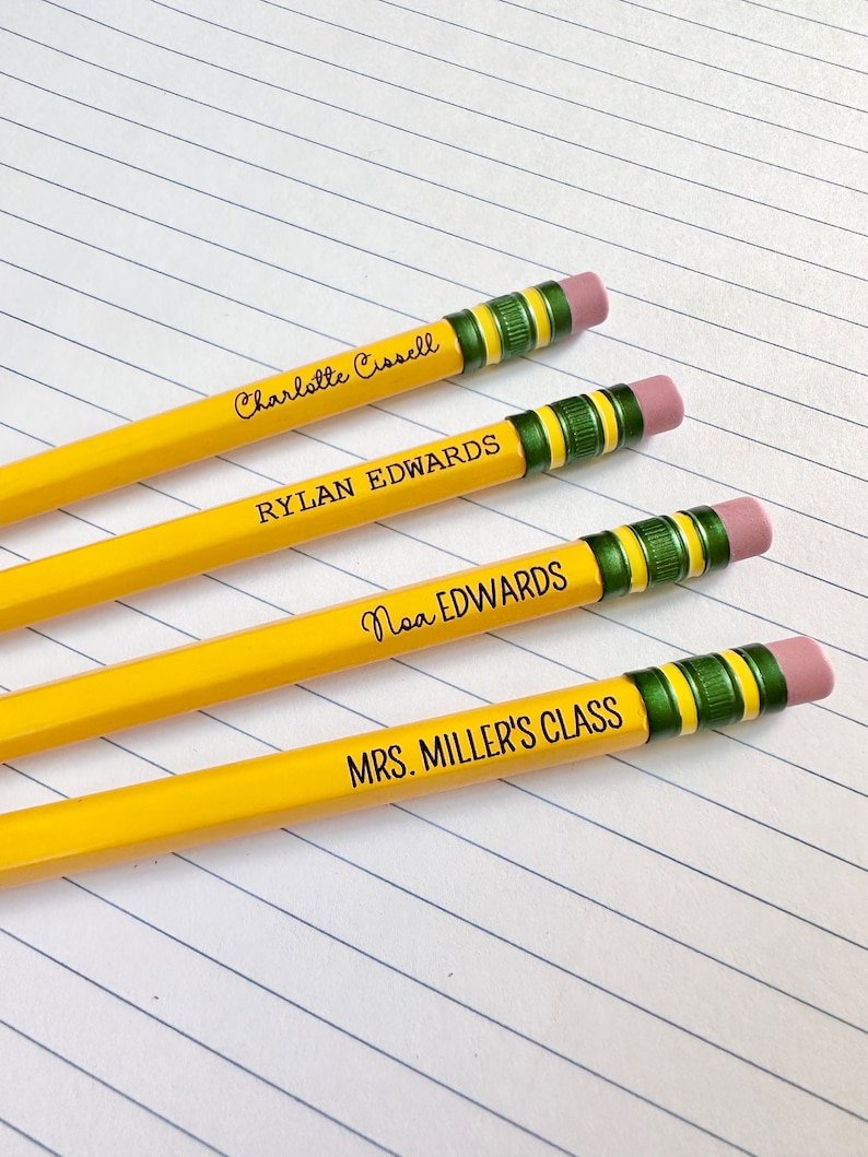 May include: Four yellow pencils with green and black striped erasers. The pencils are labeled with names: Charlotte Carroll, Rylan Edwards, Noa Edwards, and Mrs. Miller's Class.