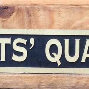 Könnte beinhalten: Ein schwarzes und goldenes Schild mit dem Text "SERVANTS' QUARTERS" in goldenen Buchstaben.