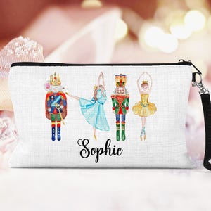 May include: White canvas makeup bag with a Nutcracker theme. The bag features a ballerina, a Nutcracker soldier, and a mouse king. The bag is personalized with the name "Sophie".