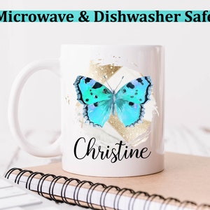 May include: White ceramic mug with a blue butterfly graphic and gold accents. The mug has the name "Christine" written on it. The mug is microwave and dishwasher safe.