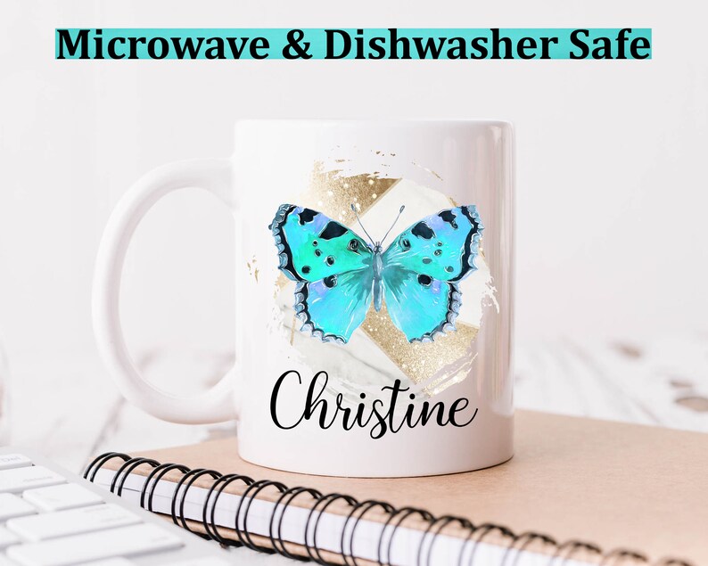 May include: White ceramic mug with a blue butterfly graphic and gold accents. The mug has the name "Christine" written on it. The mug is microwave and dishwasher safe.