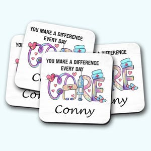 May include: A set of white square coasters with a healthcare theme. Each coaster features the word "CARE" with medical symbols and the text "YOU MAKE A DIFFERENCE EVERY DAY". The name "Conny" is also printed on the coasters.