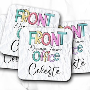 May include: Set of four square coasters with a white, textured background. Each coaster features the word "FRONT" in colorful block letters, along with "Dream Team Office Celeste" in a mix of fonts. The coasters have black edges.