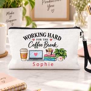 May include: A white canvas zipped pouch with a black wrist strap. The front features the text "WORKING HARD FOR THE Coffee Break" and the name "Sophie" in red. Graphics include a coffee cup, laptop, stack of books, and a potted plant.